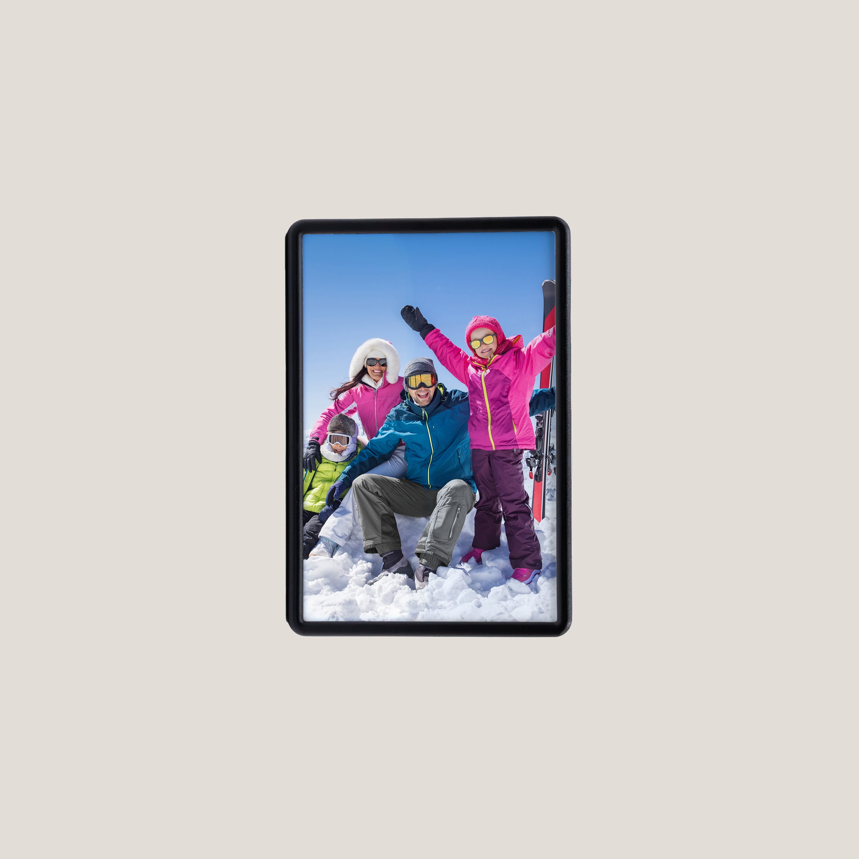 A square photo magnet with an image of a family enjoying winter sports, displayed against a plain background.