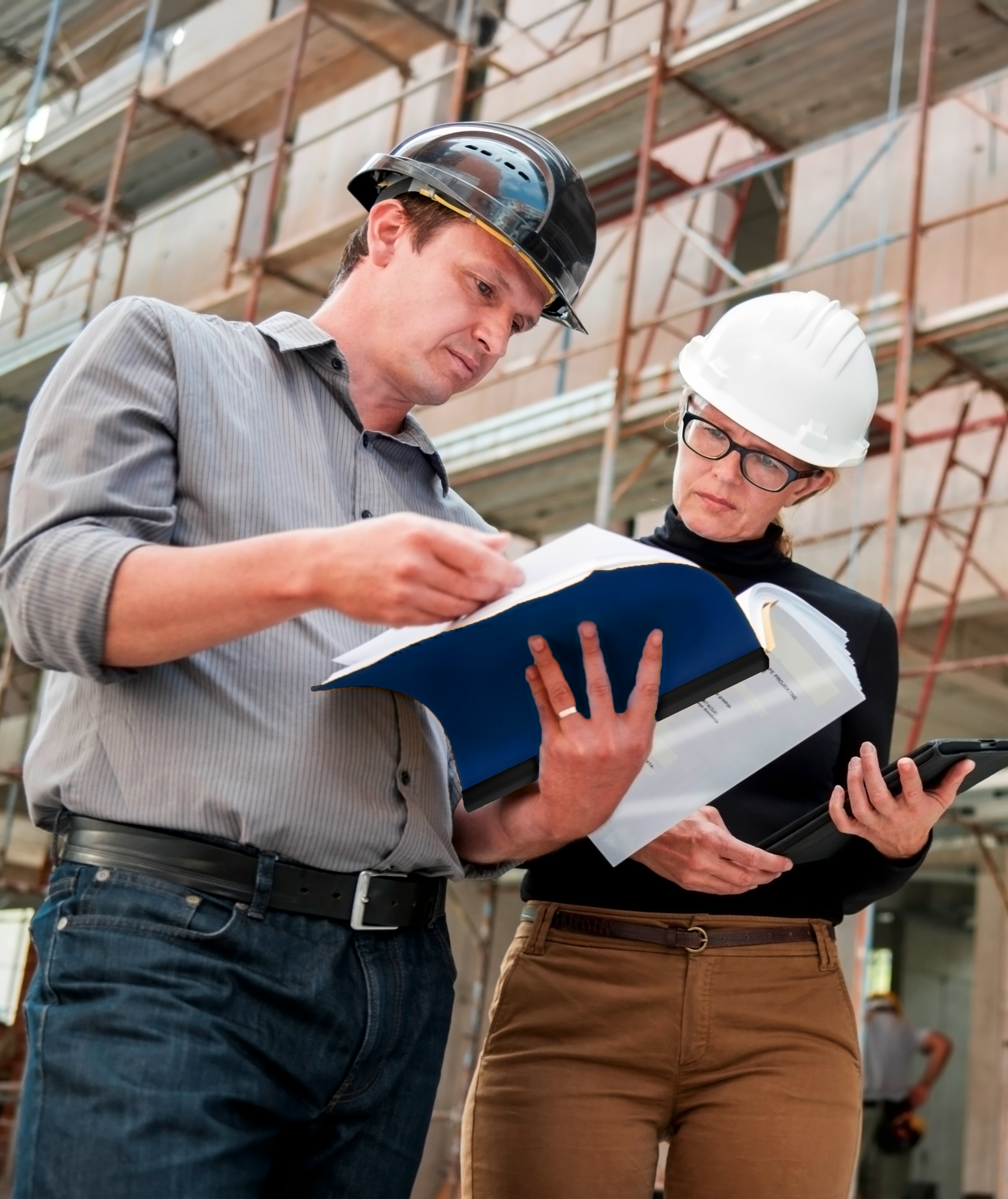 Two construction workers discussing blueprints on a building site.
