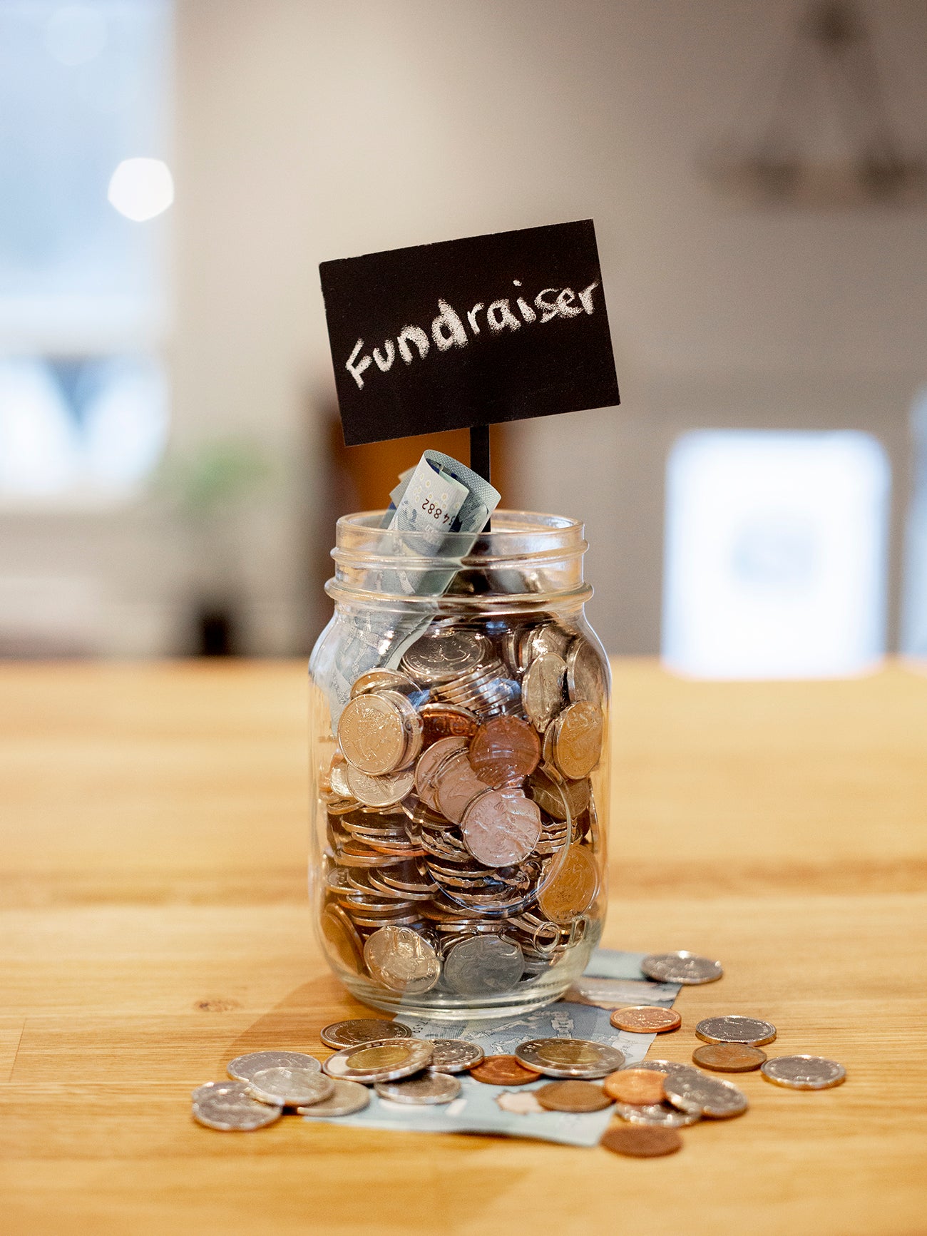 Glass jar filled with coins and dollar bills labeled Fundraiser – symbolizing Peleman photo product fundraising program where partners keep 50% revenue