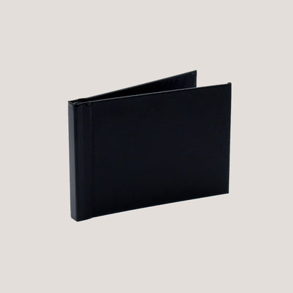 A black clamp binding photobook with a hard cover displayed open to show the binding mechanism.